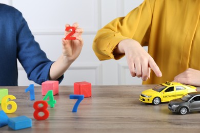 Photo of ABA therapist and girl at wooden table, closeup