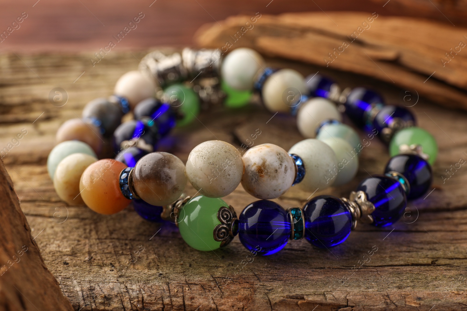 Photo of Beautiful bracelets with gemstones on wooden table, closeup