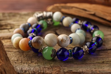 Photo of Beautiful bracelets with gemstones on wooden table, closeup