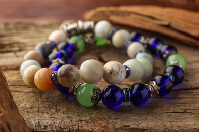 Beautiful bracelets with gemstones on wooden table, closeup