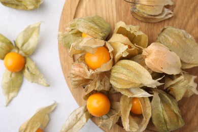 Ripe physalis fruits with calyxes on white table, flat lay. Space for text