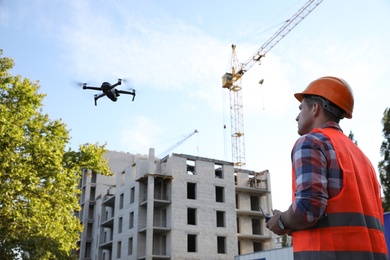 Photo of Builder operating drone with remote control at construction site. Aerial survey