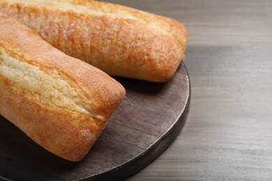 Photo of Tasty baguettes on wooden table, closeup. Space for text