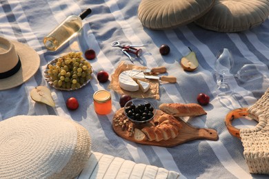 Different tasty snacks and wine on picnic blanket outdoors