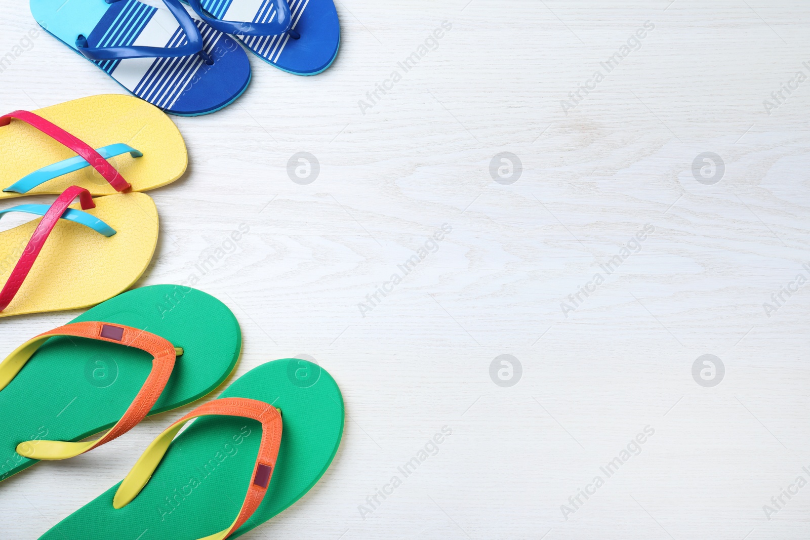 Photo of Many different stylish flip flops on white wooden background, flat lay. Space for text