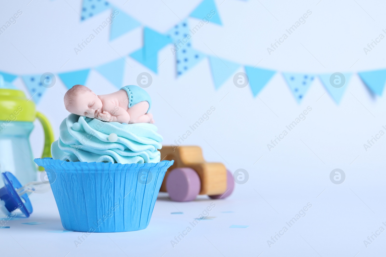 Photo of Beautifully decorated baby shower cupcake with cream and boy topper on light background. Space for text