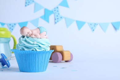 Photo of Beautifully decorated baby shower cupcake with cream and boy topper on light background. Space for text