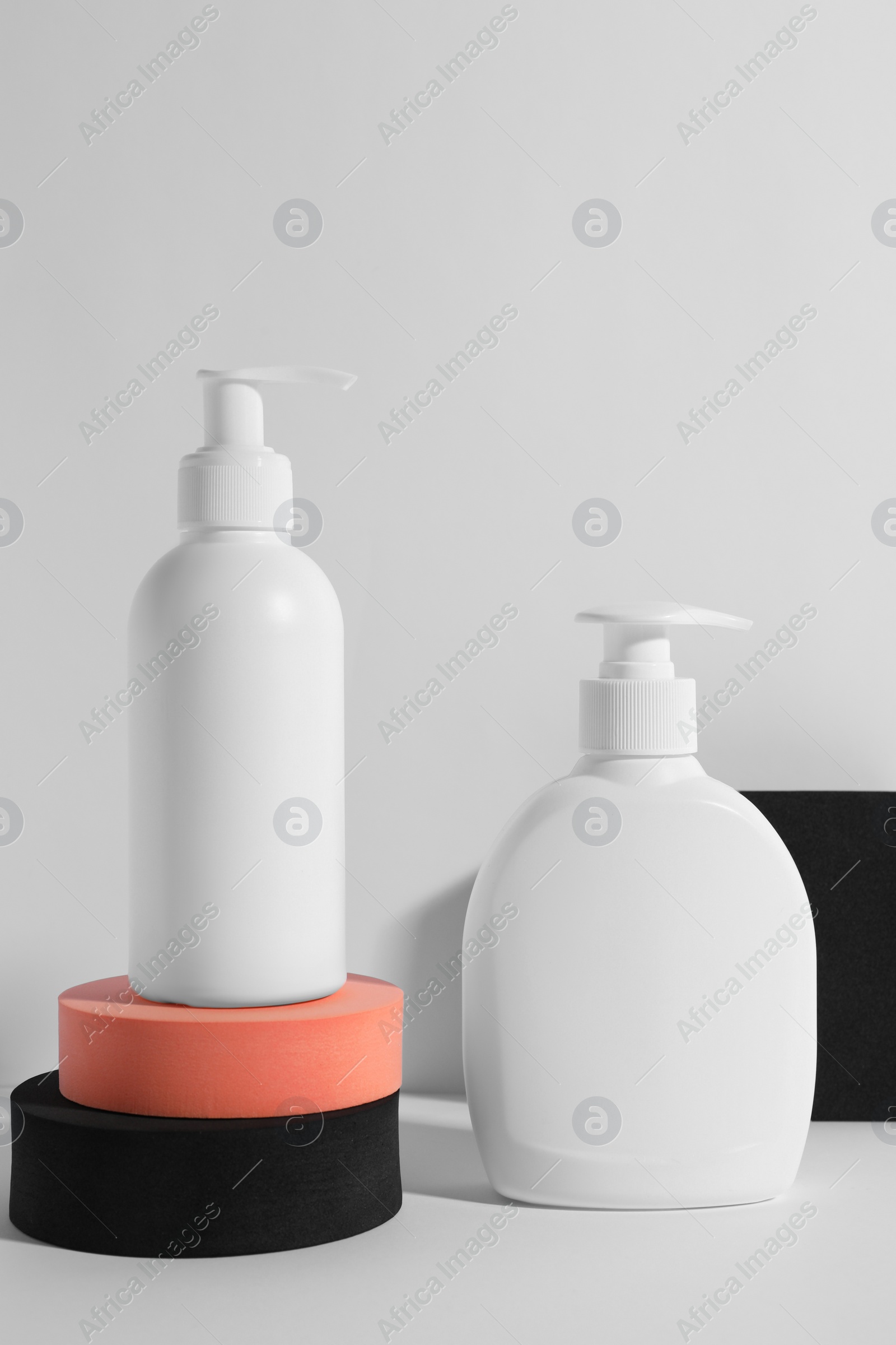 Photo of Bottles with different cosmetic products and podiums on white background