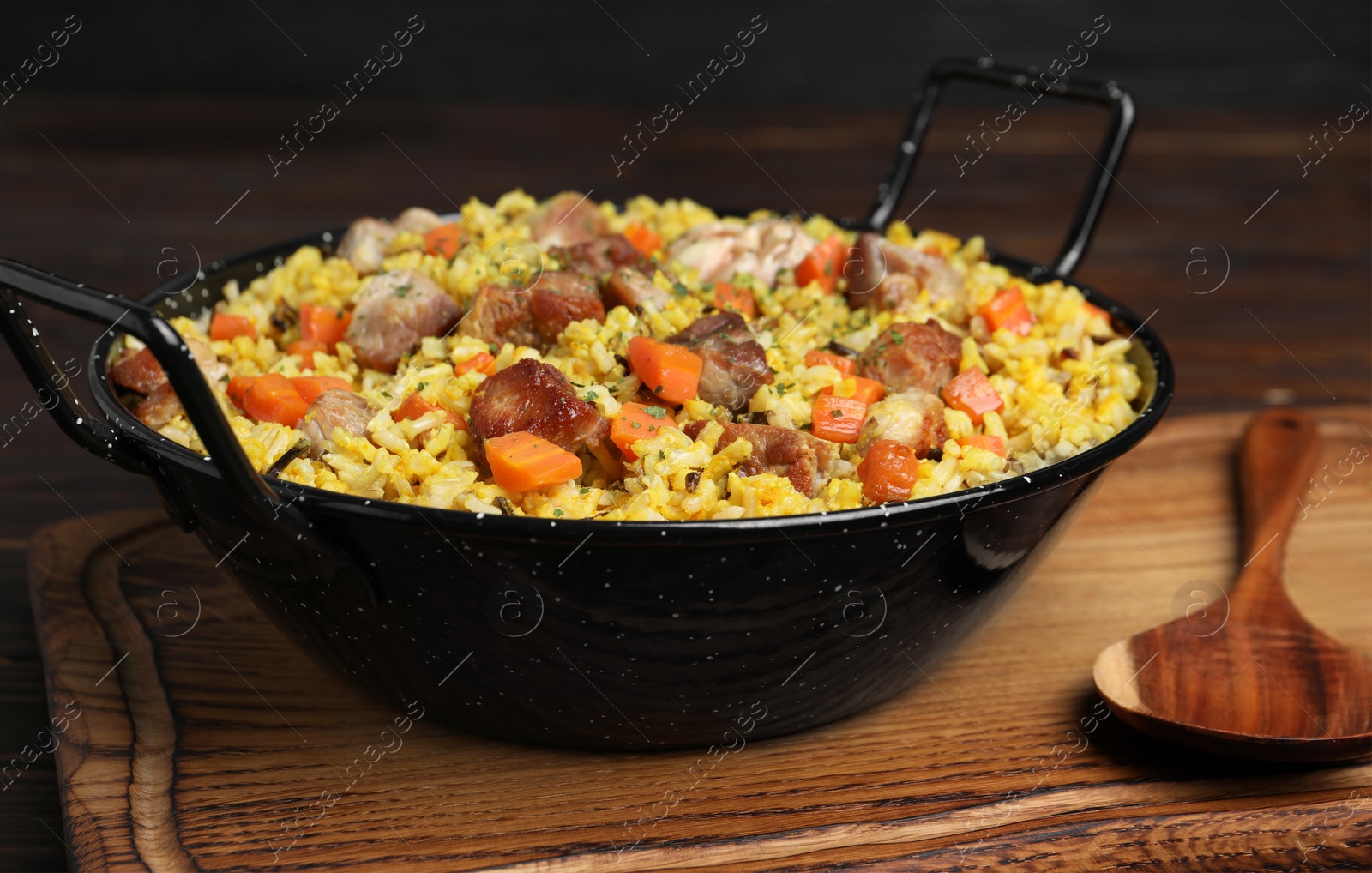 Photo of Delicious pilaf with meat and carrot served on wooden board, closeup