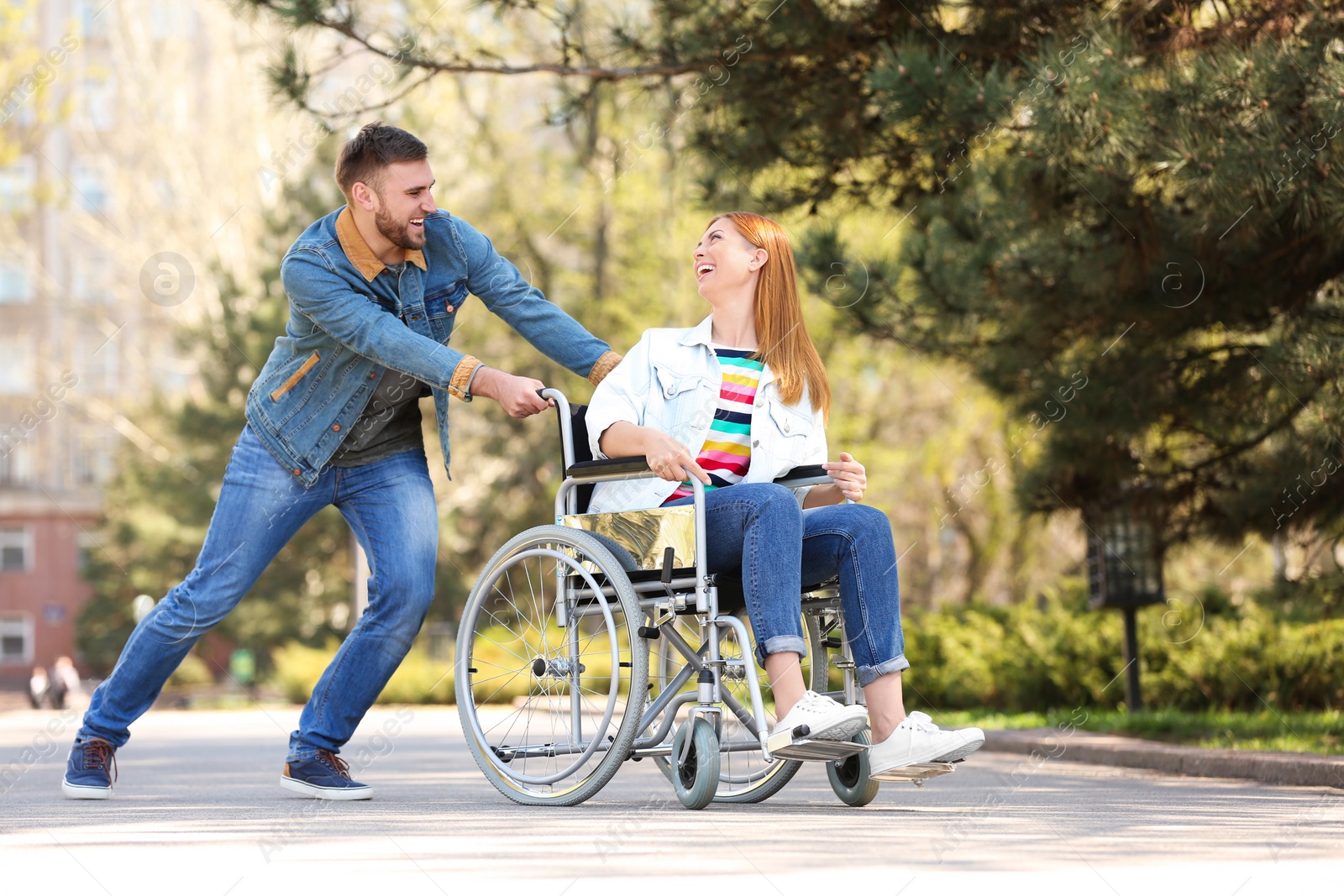 Photo of Happy woman in wheelchair and young man at park on sunny day