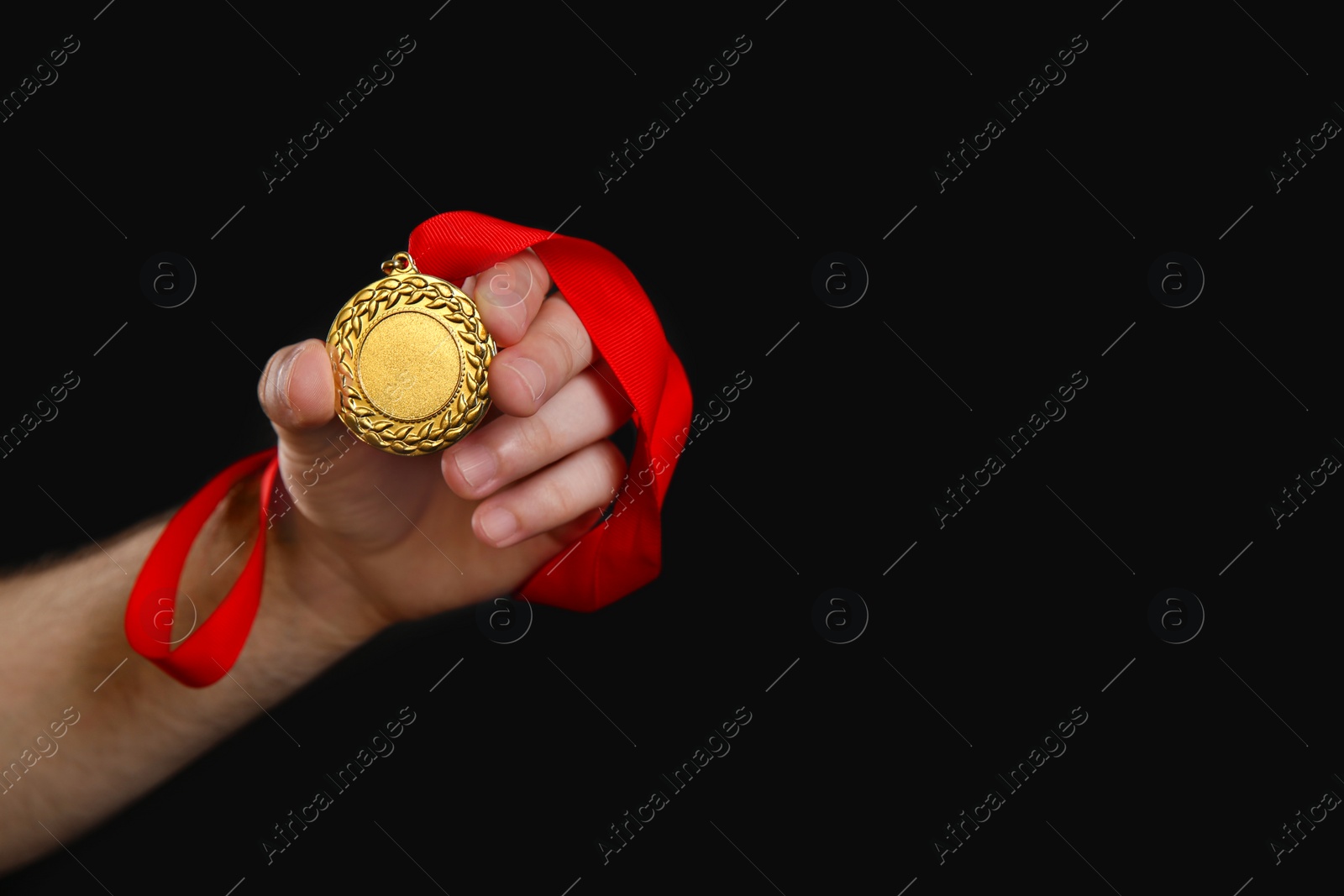 Photo of Man holding golden medal on black background, closeup. Space for design