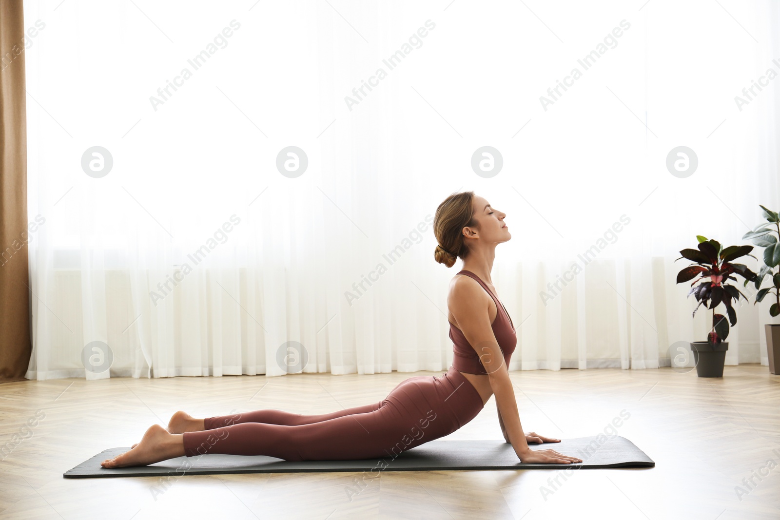 Photo of Young woman practicing high cobra asana in yoga studio. Bhujangasana pose