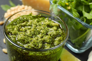 Photo of Glass of tasty arugula pesto on table, closeup