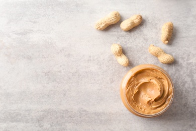 Photo of Jar with creamy peanut butter on light background