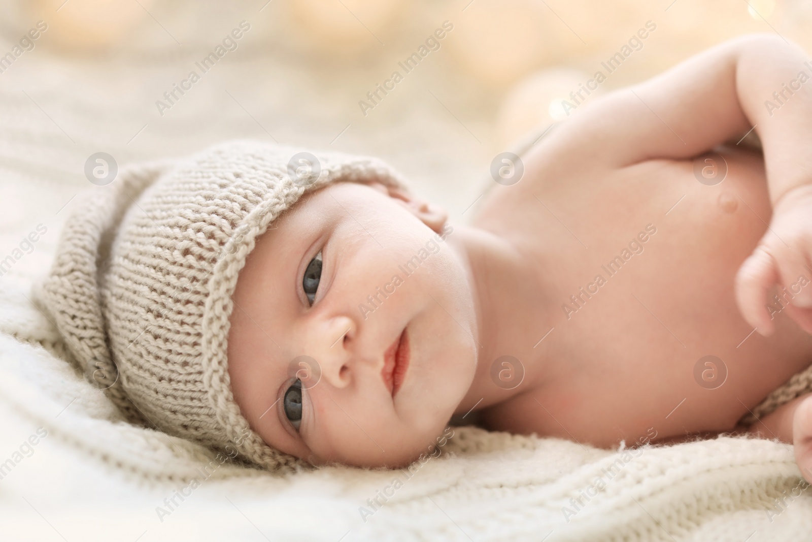 Photo of Adorable newborn baby in hat lying on bed