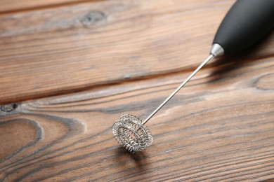 Photo of Black milk frother wand on wooden table, closeup. Space for text