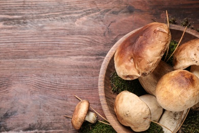 Photo of Fresh wild porcini mushrooms on wooden table, top view. Space for text