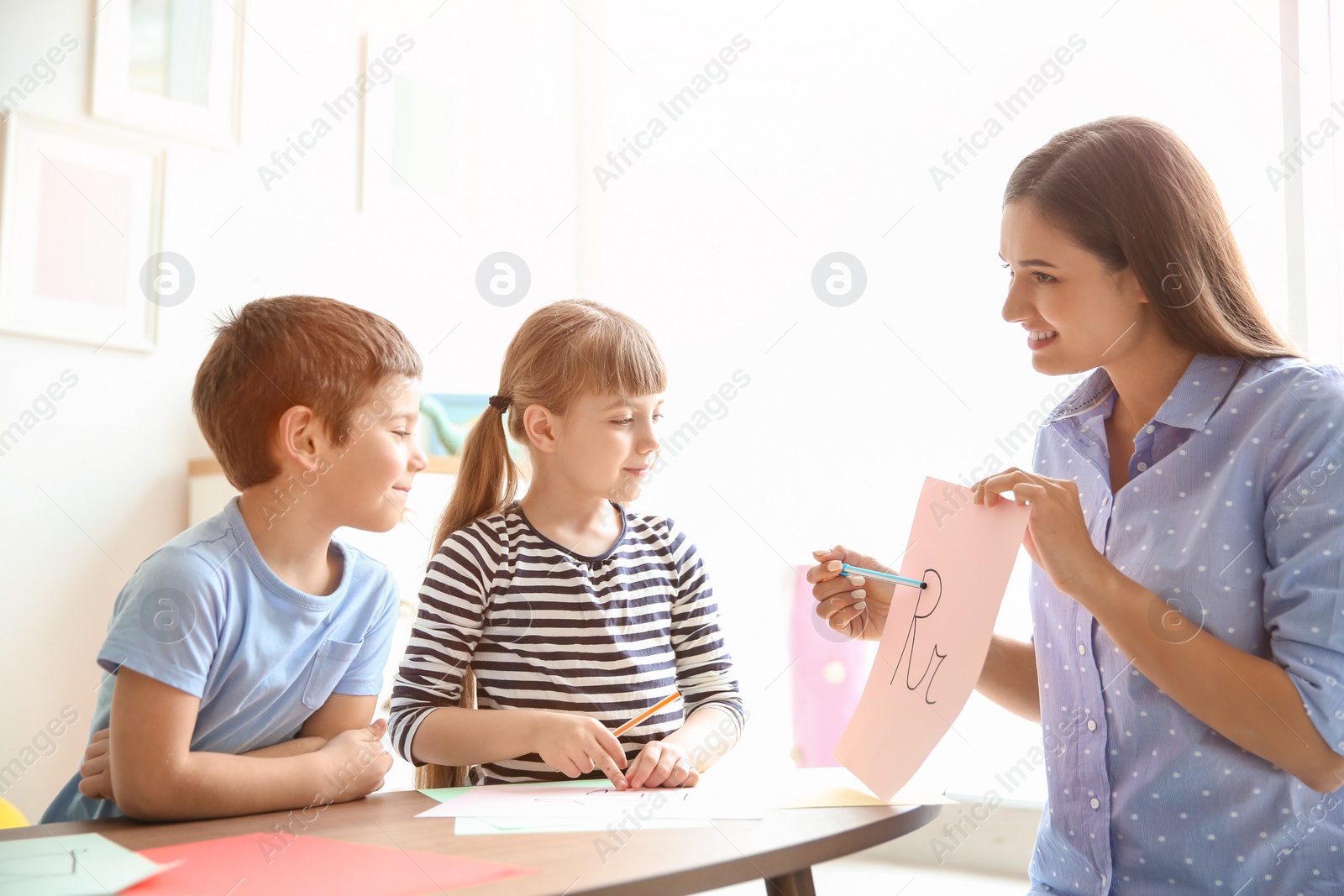 Photo of Cute little children with teacher in classroom at school