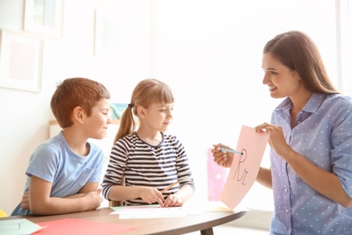 Photo of Cute little children with teacher in classroom at school