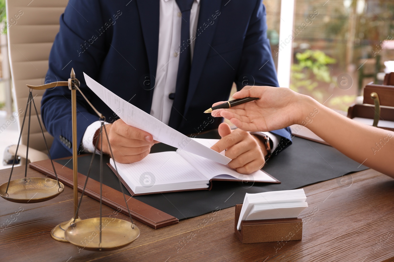 Photo of Lawyer working with client at table in office, focus on hands