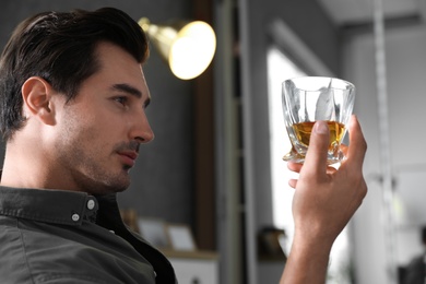 Young man with glass of whiskey at home