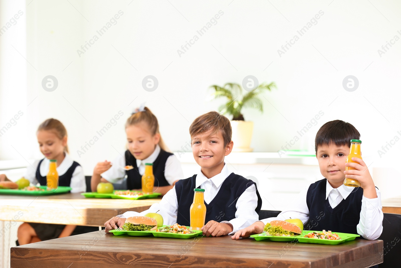 Photo of Happy children eating healthy food for lunch in school canteen