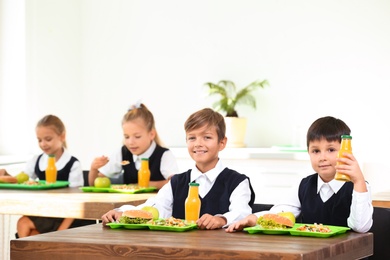 Photo of Happy children eating healthy food for lunch in school canteen