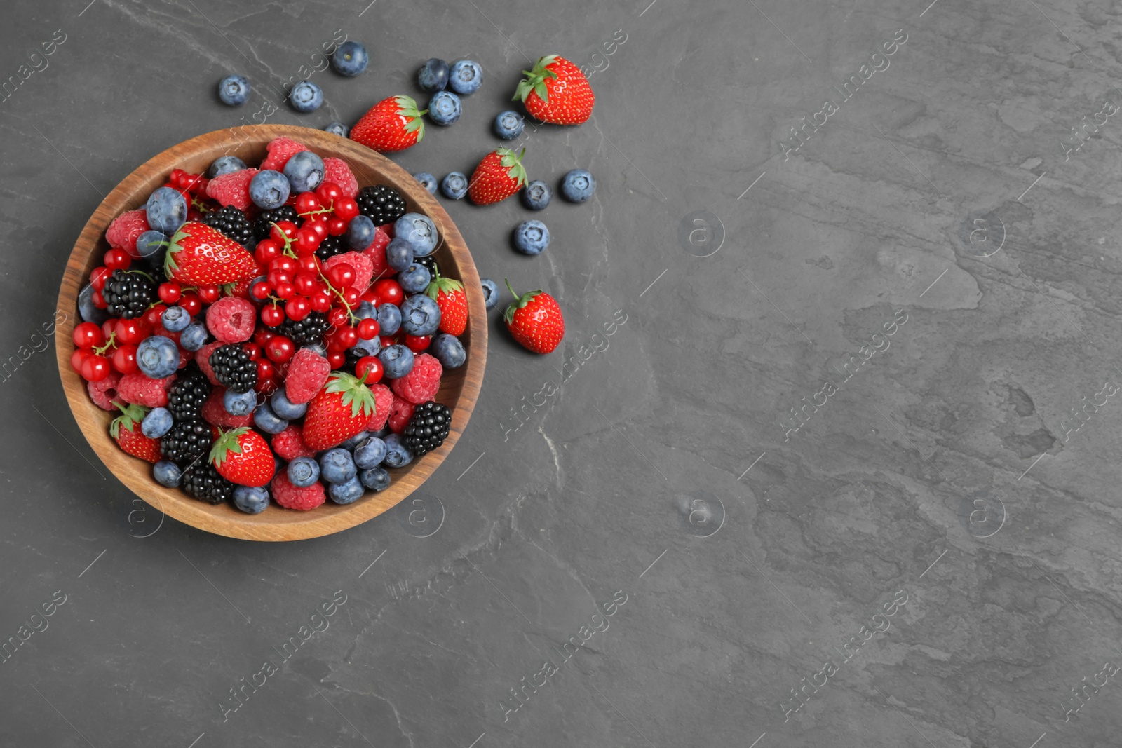 Photo of Mix of different fresh berries in bowl on grey table, flat lay. Space for text