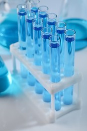 Photo of Test tubes with blue liquid on light background, closeup