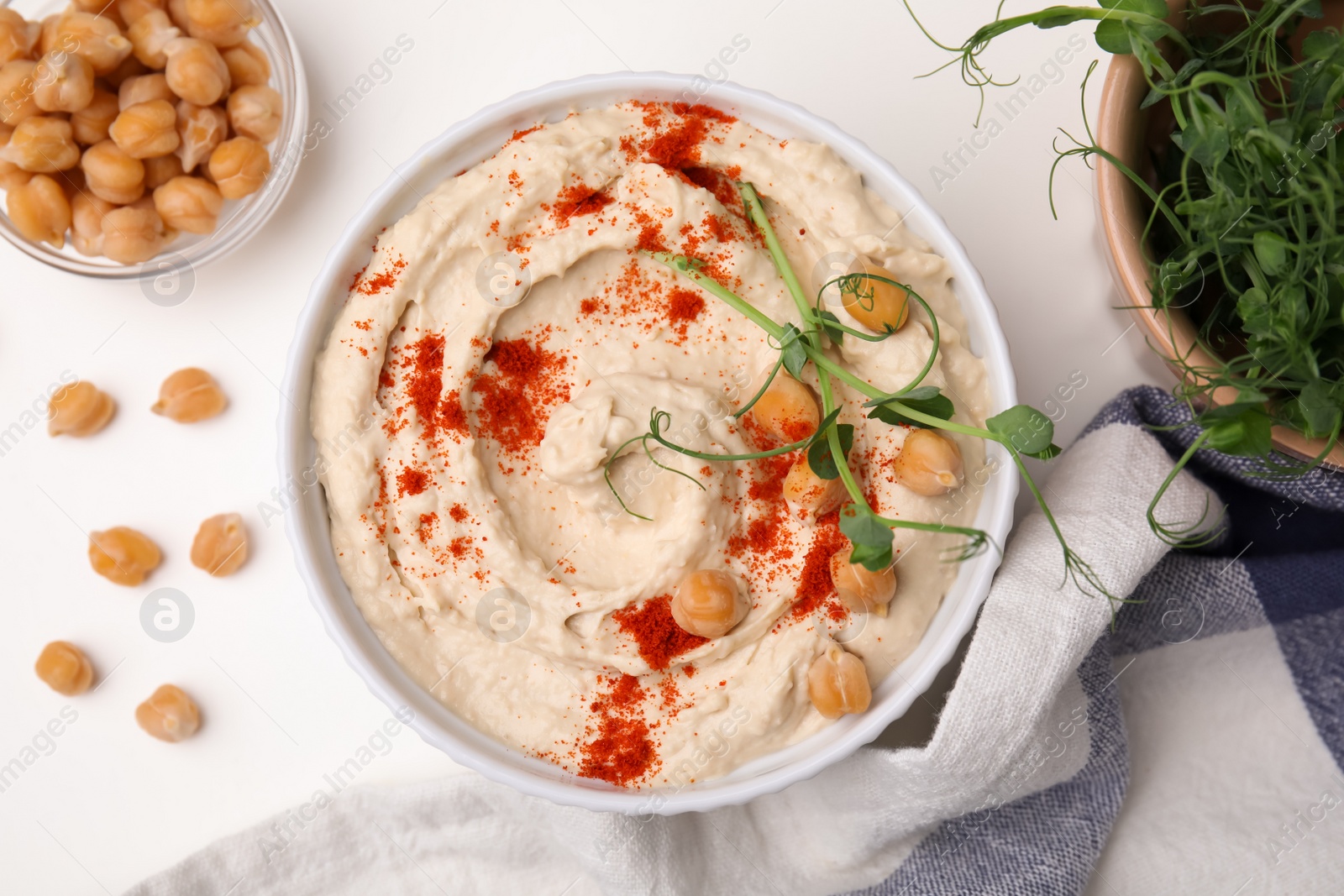 Photo of Delicious hummus with chickpeas and paprika served on white table, flat lay