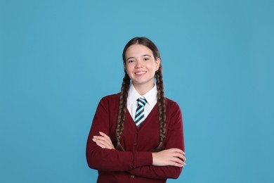 Teenage girl wearing school uniform on light blue background