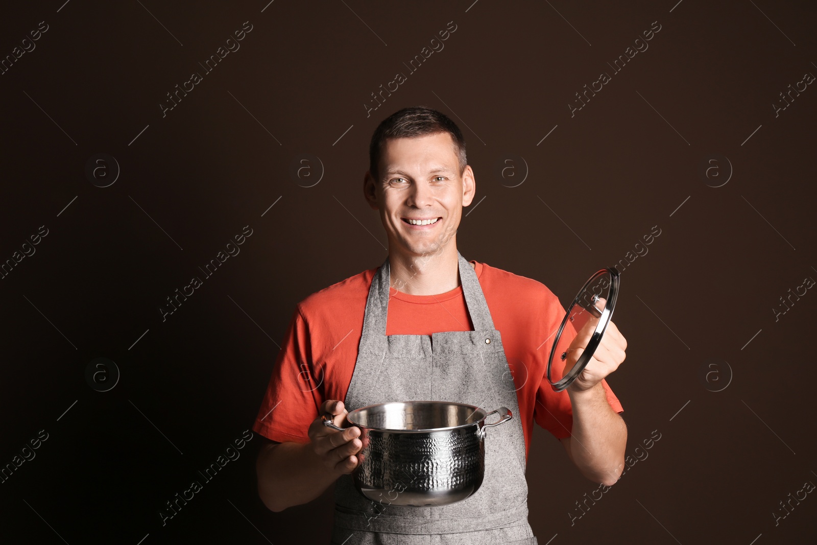 Photo of Happy man with cooking pot on brown background