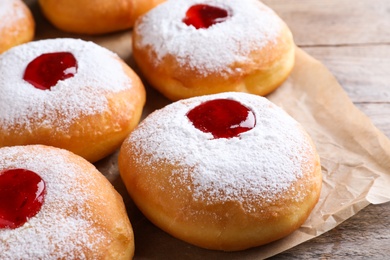 Photo of Hanukkah doughnuts with jelly and sugar powder on wooden table, closeup