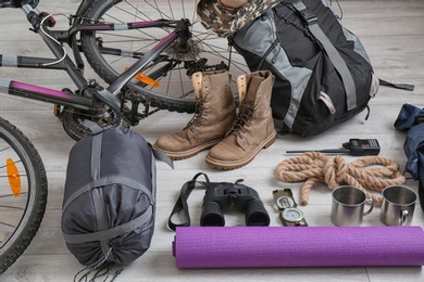 Photo of Sleeping bag, bicycle and set of camping equipment on wooden floor
