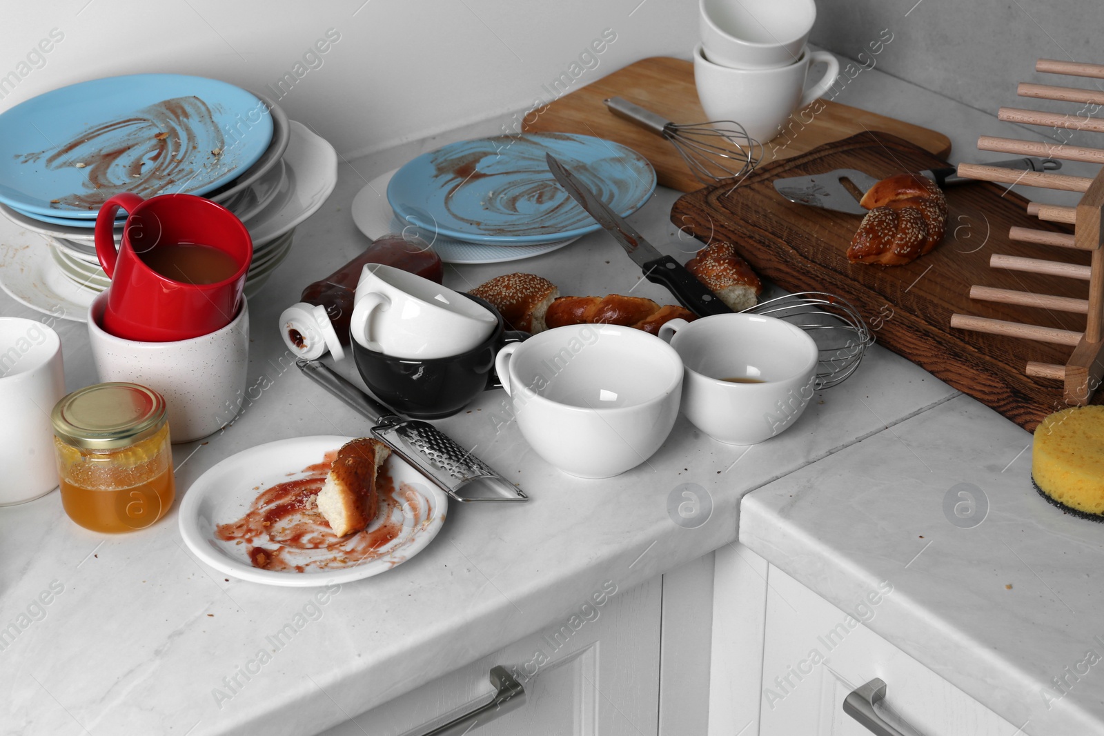 Photo of Many dirty utensils, dishware and food leftovers on countertop in messy kitchen