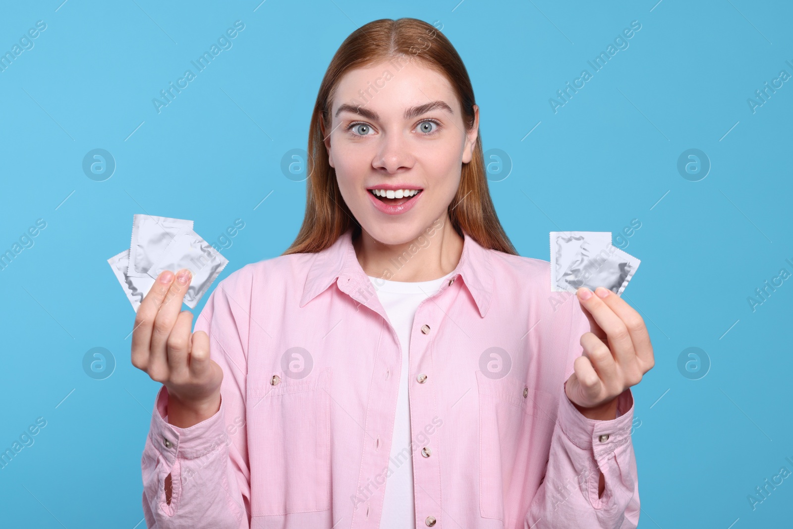 Photo of Woman holding condoms on turquoise background. Safe sex