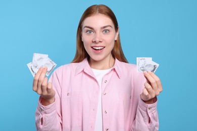 Photo of Woman holding condoms on turquoise background. Safe sex