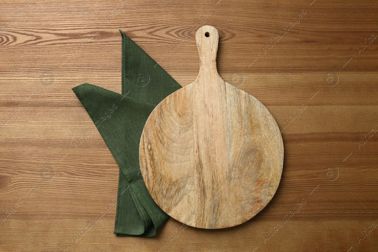 Photo of Empty wooden board and green napkin on table, top view