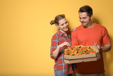 Photo of Attractive young couple with delicious pizza on color background