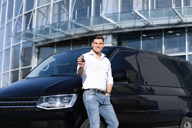 Photo of Man with key near car on city street. Buying new auto