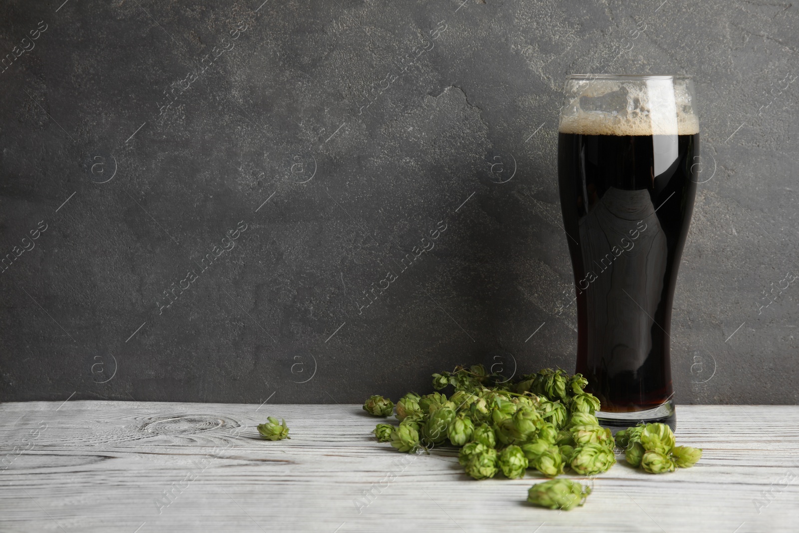 Photo of Composition with tasty beer and fresh green hops on wooden table. Space for text