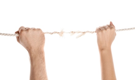 Man and woman pulling frayed rope at breaking point on white background