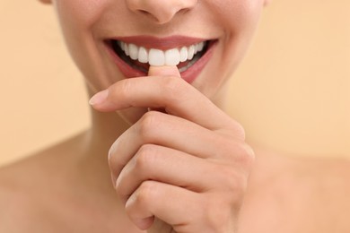 Photo of Woman with beautiful lips biting her finger on beige background, closeup