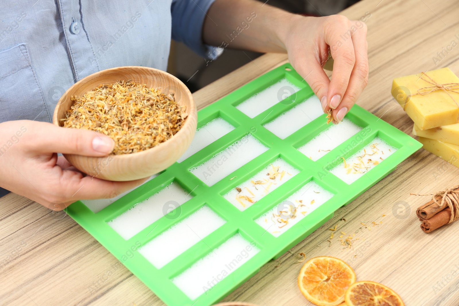 Photo of Woman making natural handmade soap at wooden table, closeup