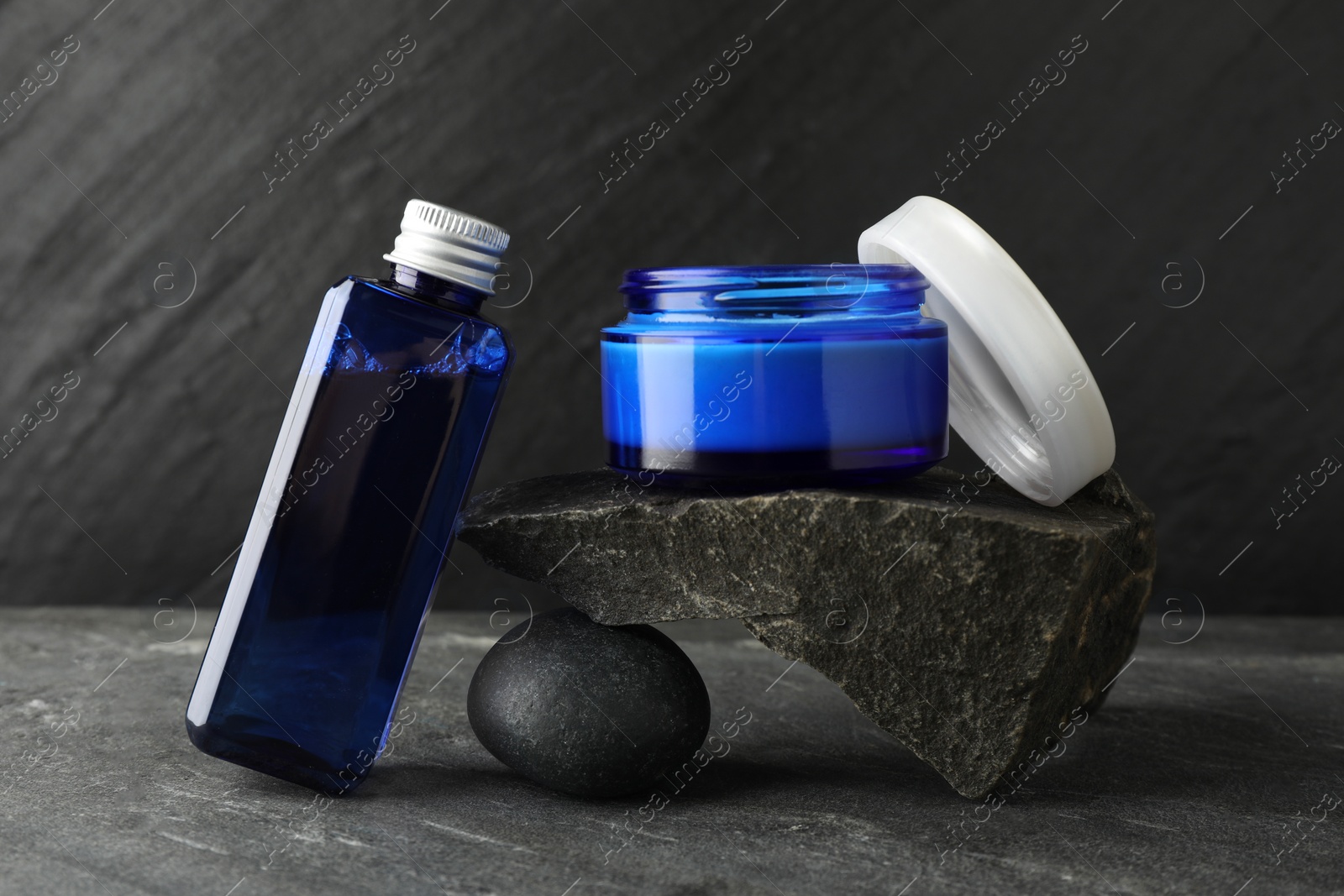 Photo of Cosmetic products and stones on grey background