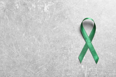 Photo of Green ribbon on grey background, top view. Cancer awareness