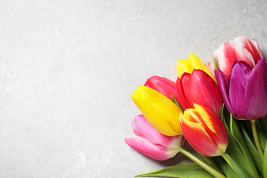 Photo of Beautiful spring tulips on light grey stone table, flat lay. Space for text