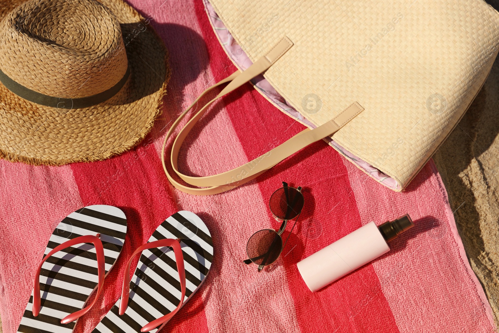 Photo of Straw hat, bag and other beach items on sandy seashore, closeup. View from above