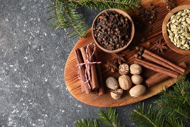 Different spices and fir branches on dark gray table, flat lay. Space for text