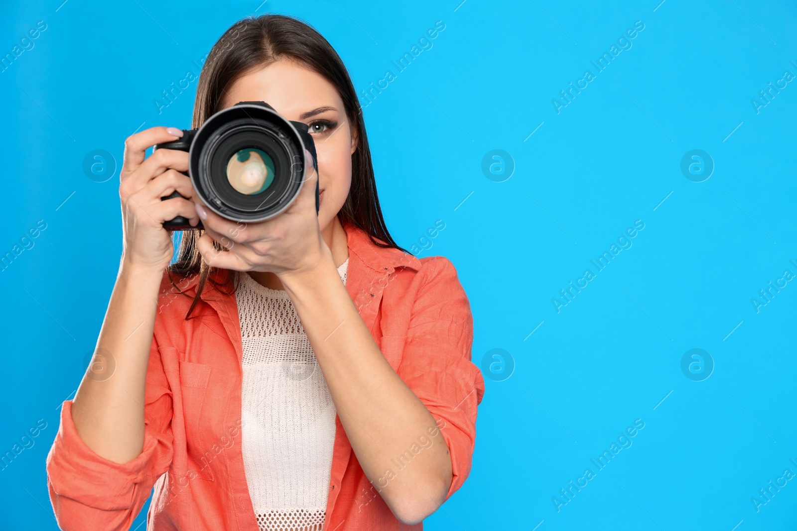 Photo of Professional photographer working on light blue background in studio. Space for text